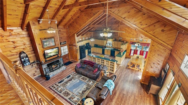 living room with wood-type flooring, beam ceiling, ceiling fan, and wood walls