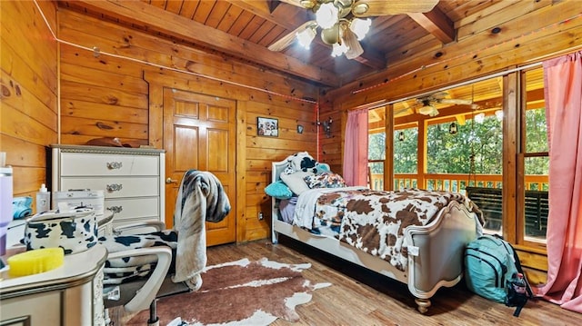 bedroom with ceiling fan, wooden walls, beam ceiling, wooden ceiling, and hardwood / wood-style floors