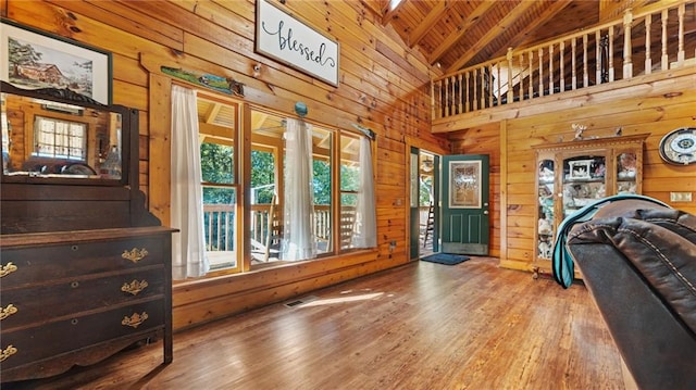 interior space with beamed ceiling, hardwood / wood-style floors, high vaulted ceiling, and wood walls