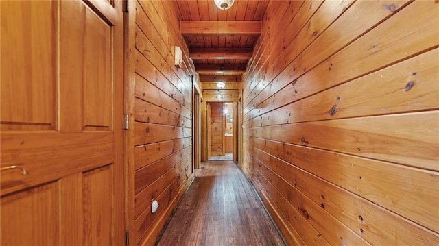 corridor featuring beamed ceiling, wooden walls, dark wood-type flooring, and wood ceiling