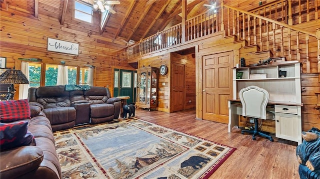 living room with a skylight, light hardwood / wood-style flooring, high vaulted ceiling, wooden ceiling, and wood walls