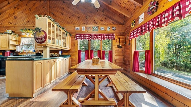 dining area featuring vaulted ceiling with beams, wood walls, light wood-type flooring, and wooden ceiling