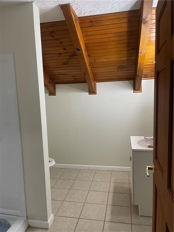 bathroom featuring beam ceiling, tile patterned flooring, vanity, and toilet