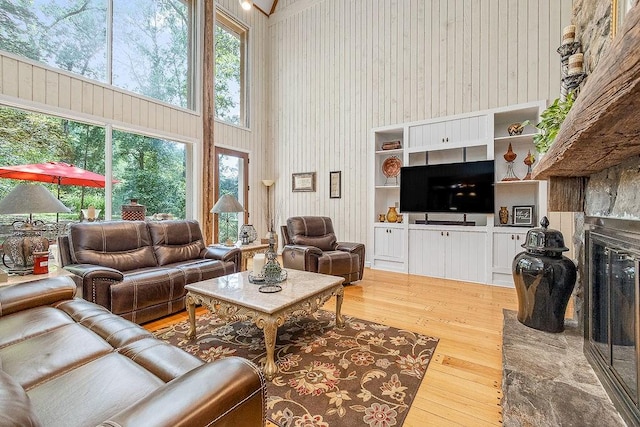 living room with built in features, a wealth of natural light, hardwood / wood-style floors, and a high ceiling