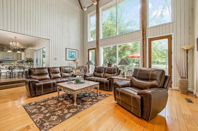 living room featuring wood-type flooring, a notable chandelier, and high vaulted ceiling