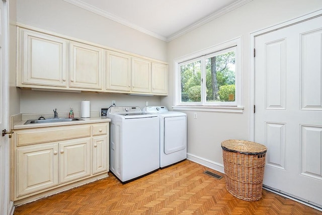 clothes washing area featuring light parquet floors, sink, washing machine and dryer, and cabinets