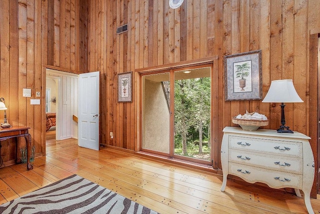 living area with light hardwood / wood-style flooring, wooden walls, and a high ceiling