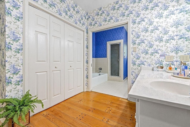 bathroom with wood-type flooring, a bath, and vanity