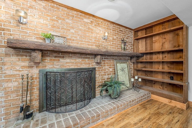 unfurnished living room featuring brick wall, a fireplace, and light wood-type flooring