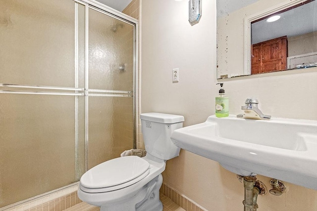 bathroom with toilet, tile patterned floors, and a shower with door