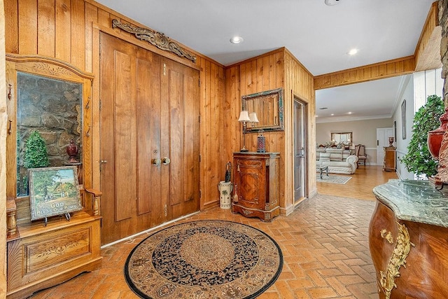 foyer entrance featuring light hardwood / wood-style floors, crown molding, and wooden walls