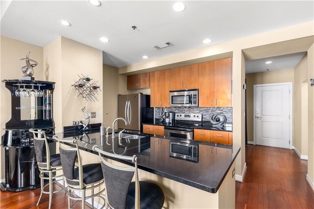 kitchen with kitchen peninsula, appliances with stainless steel finishes, dark hardwood / wood-style floors, and sink