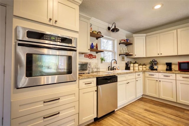 kitchen featuring sink, light stone counters, white cabinetry, appliances with stainless steel finishes, and light hardwood / wood-style floors