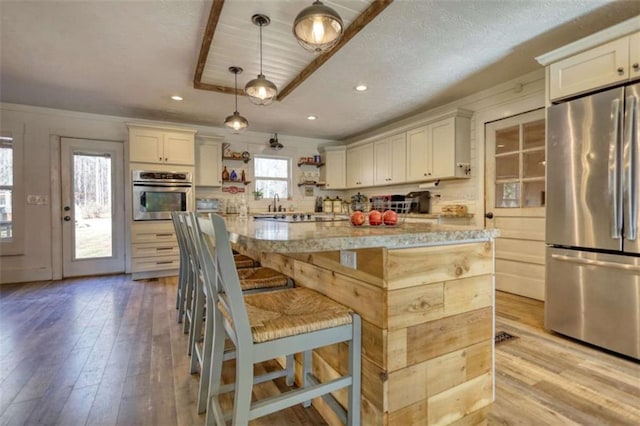 kitchen featuring a kitchen island, decorative light fixtures, a kitchen breakfast bar, stainless steel appliances, and light stone countertops