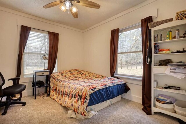 bedroom with multiple windows, ornamental molding, light colored carpet, and ceiling fan