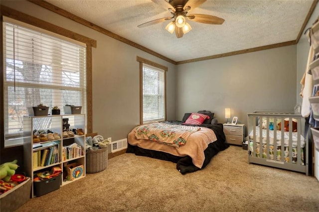 carpeted bedroom featuring ceiling fan, ornamental molding, and a textured ceiling