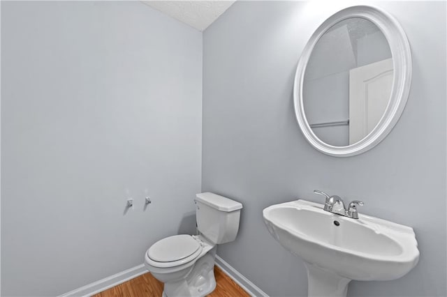 bathroom featuring hardwood / wood-style floors, a textured ceiling, toilet, and sink