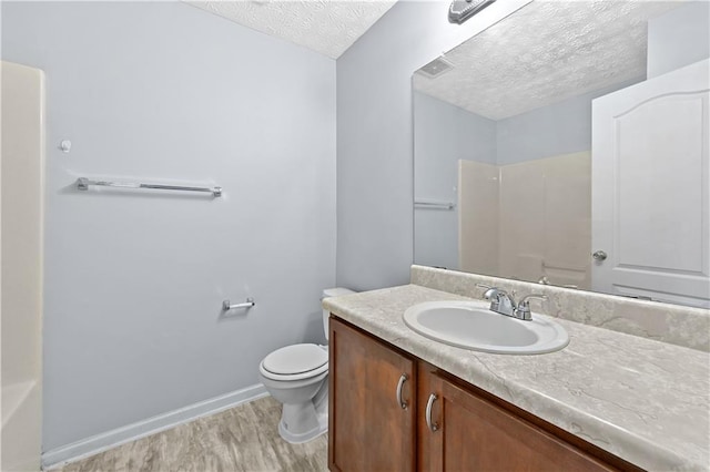 bathroom with vanity, hardwood / wood-style floors, a textured ceiling, and toilet