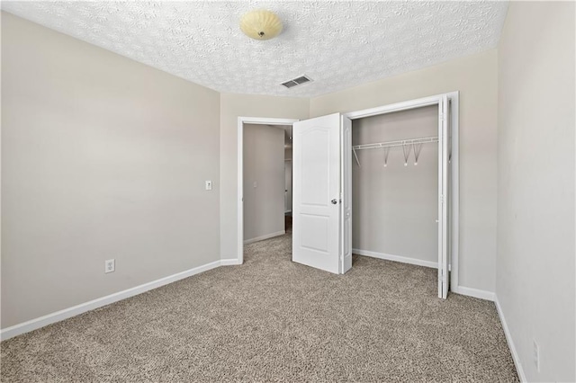 unfurnished bedroom featuring light carpet, a textured ceiling, and a closet