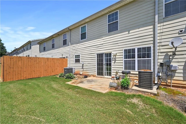 rear view of house featuring a lawn, central AC unit, and a patio