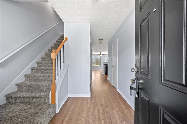 foyer with ceiling fan, wood-type flooring, and a textured ceiling