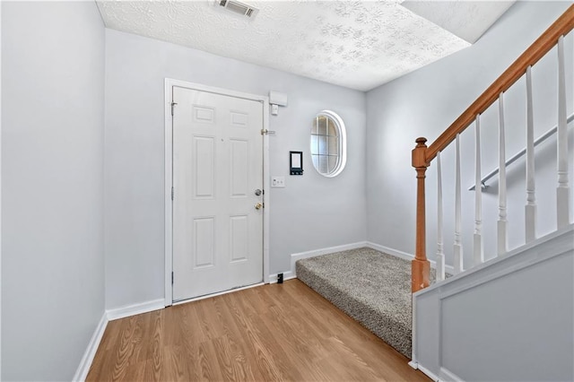 foyer entrance with light wood-type flooring and a textured ceiling