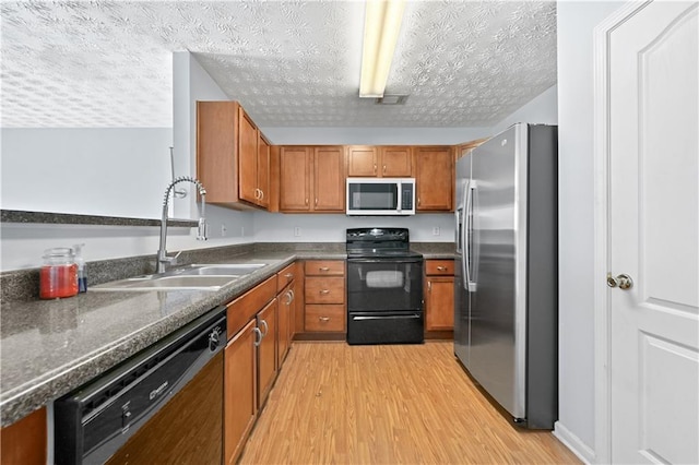 kitchen featuring sink, black appliances, a textured ceiling, and light wood-type flooring