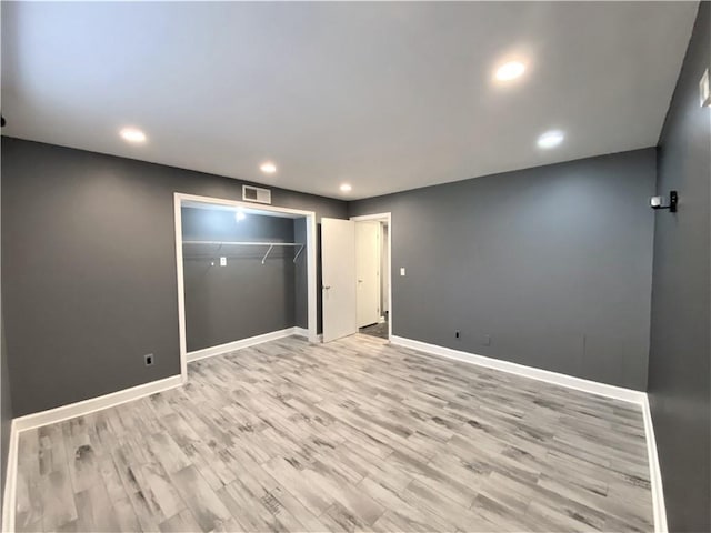 unfurnished bedroom featuring recessed lighting, baseboards, light wood-type flooring, visible vents, and a closet