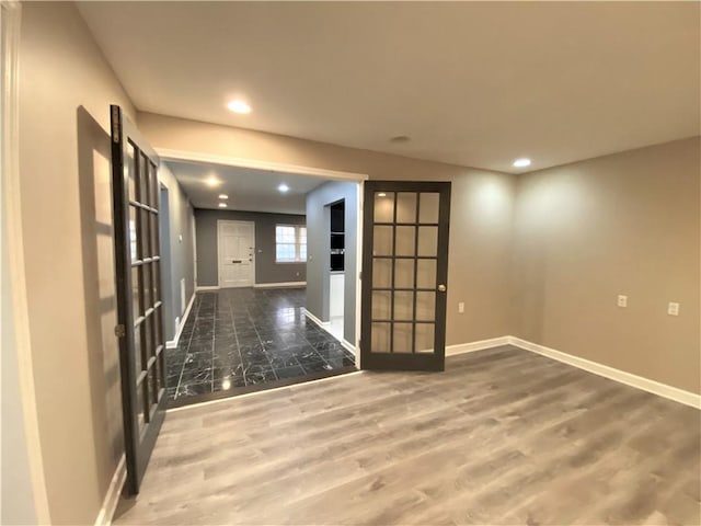 empty room featuring baseboards, recessed lighting, wood finished floors, and french doors
