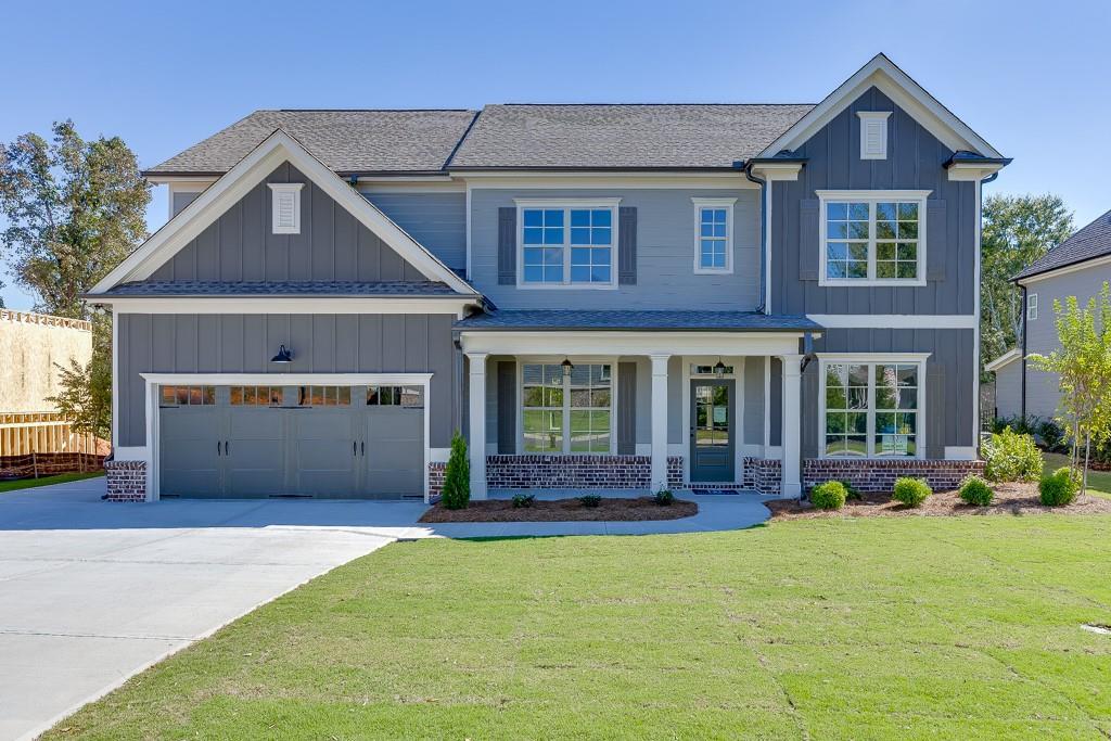 craftsman-style home featuring covered porch, a garage, and a front lawn