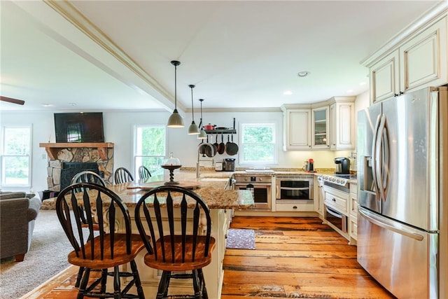 kitchen with a breakfast bar area, light stone counters, a healthy amount of sunlight, and stainless steel appliances