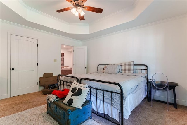 carpeted bedroom with ceiling fan, ornamental molding, and a tray ceiling