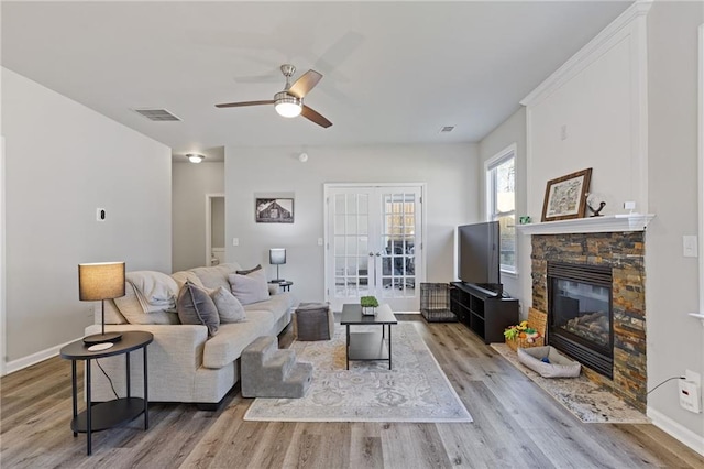 living area with visible vents, wood finished floors, french doors, a fireplace, and baseboards