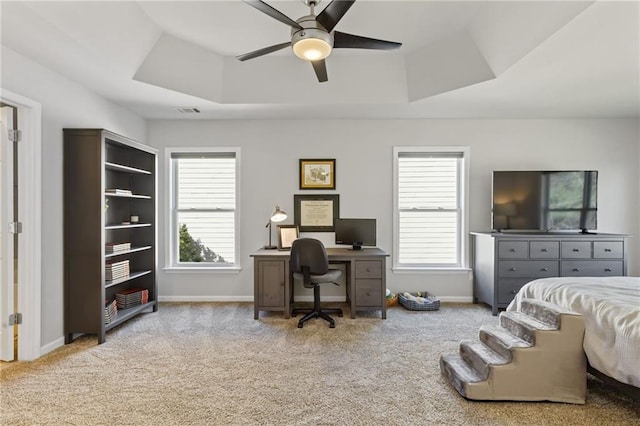 carpeted bedroom with a raised ceiling, visible vents, baseboards, and ceiling fan