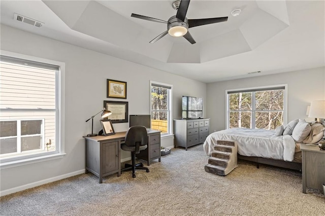 bedroom featuring a tray ceiling, carpet flooring, baseboards, and visible vents