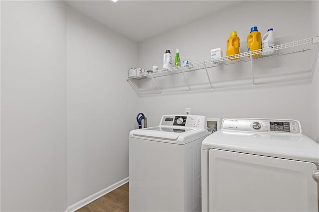 laundry area featuring washing machine and clothes dryer, laundry area, baseboards, and wood finished floors