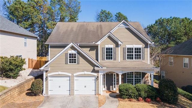 traditional home with fence, driveway, an attached garage, covered porch, and stone siding