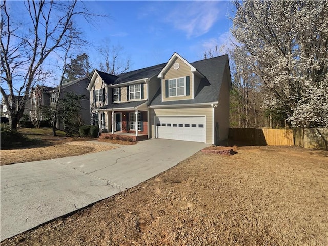 traditional-style house with driveway, covered porch, an attached garage, and fence