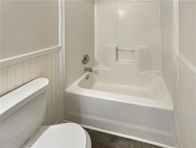 full bathroom featuring toilet and a wainscoted wall