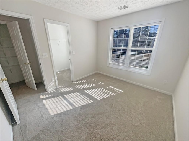 unfurnished bedroom with visible vents, multiple windows, a textured ceiling, and baseboards