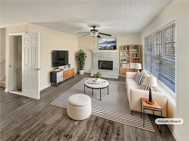 living room with a brick fireplace, baseboards, a ceiling fan, and wood finished floors