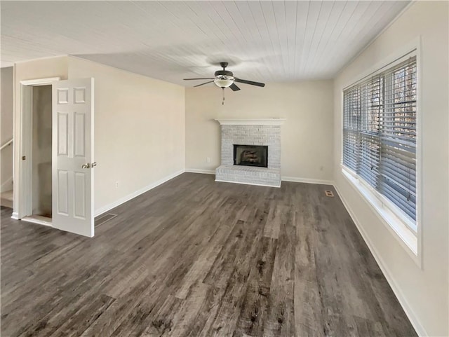 unfurnished living room featuring baseboards, a fireplace, a ceiling fan, and dark wood-type flooring