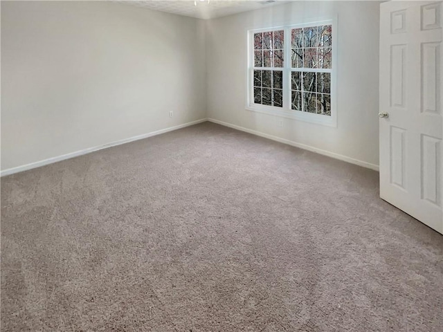 carpeted empty room featuring baseboards