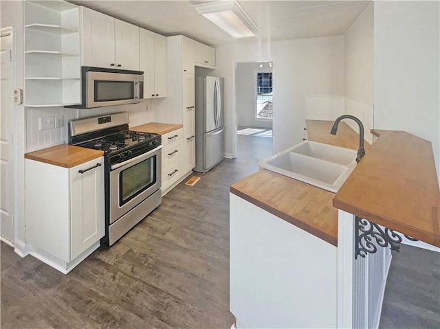 kitchen with stainless steel appliances, butcher block countertops, dark wood-style flooring, and a sink