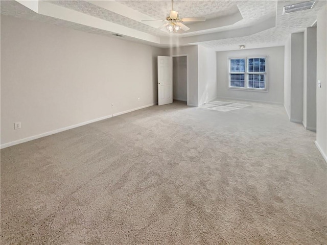 unfurnished bedroom with visible vents, baseboards, a raised ceiling, a textured ceiling, and carpet floors