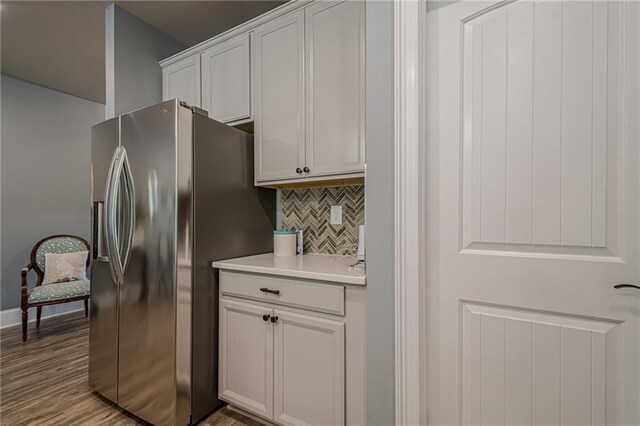 3715 Bridges Ct, Cumming, GA 30040 - kitchen featuring stainless steel fridge, backsplash, light countertops, wood finished floors, and white cabinetry