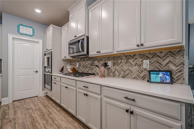 3715 Bridges Ct, Cumming, GA 30040 - kitchen with stainless steel appliances, tasteful backsplash, light stone counters, white cabinets, and recessed lighting