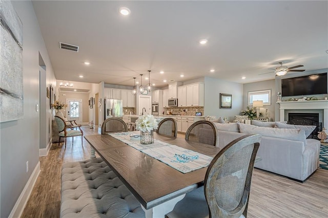 3715 Bridges Ct, Cumming, GA 30040 - dining space with ceiling fan, baseboards, light wood finished floors, recessed lighting, and a fireplace