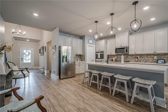 3715 Bridges Ct, Cumming, GA 30040 - kitchen with stainless steel appliances, decorative backsplash, light countertops, a breakfast bar, and recessed lighting