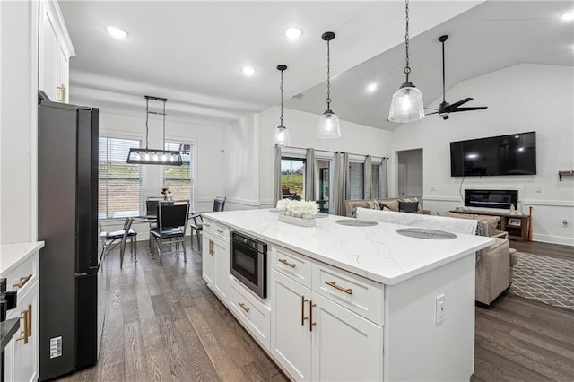 kitchen featuring built in microwave, freestanding refrigerator, dark wood-type flooring, white cabinets, and a center island